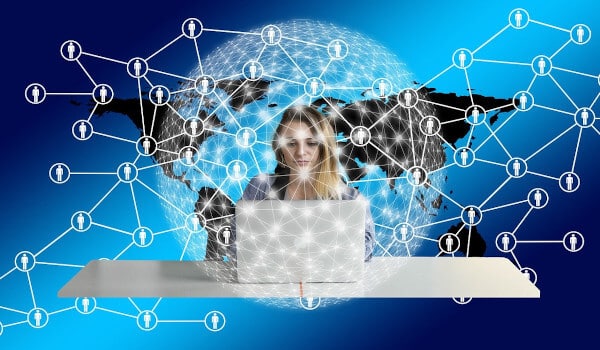 Woman using a laptop with network connections overlaid on a world map in the background.