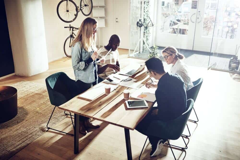 A group of people collaborating at a wooden table in a well-lit office with bicycles on the wall.