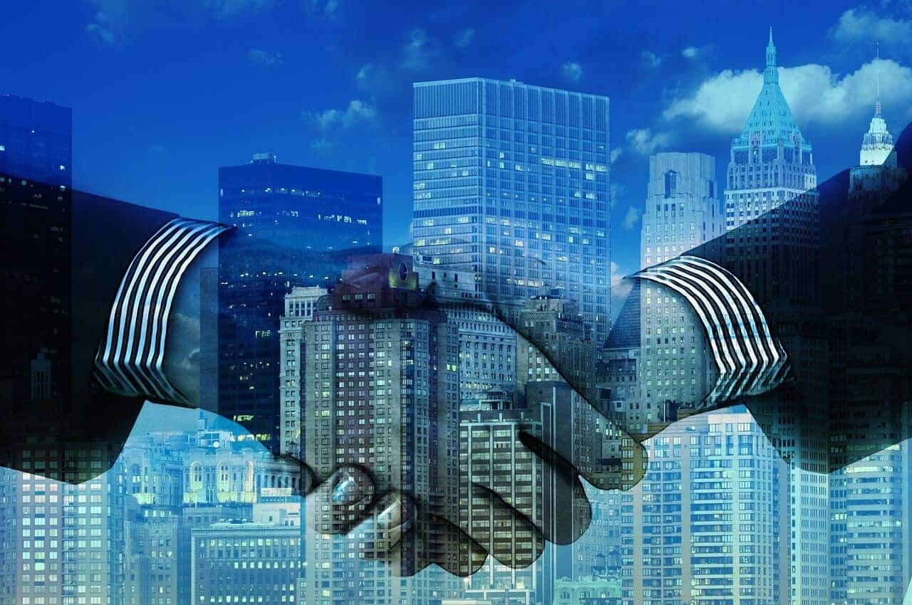 Two hands shaking in front of a cityscape, symbolizing business agreement or partnership.