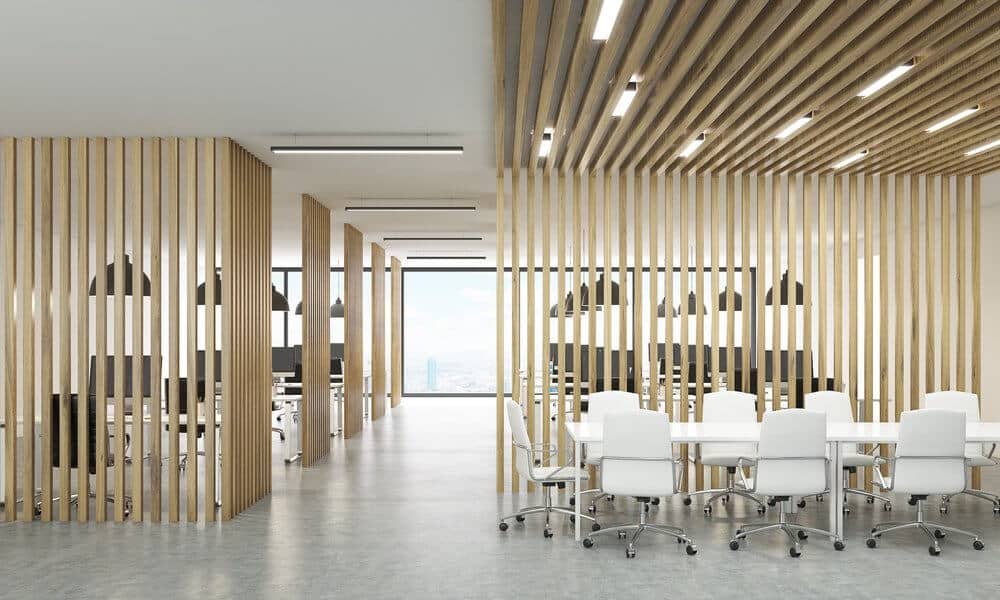 Modern office space with wooden slat walls, white desks, and chairs, featuring large windows with a city view.