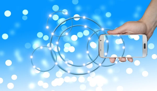 Hand holding a transparent phone against a blue background with circular light patterns.