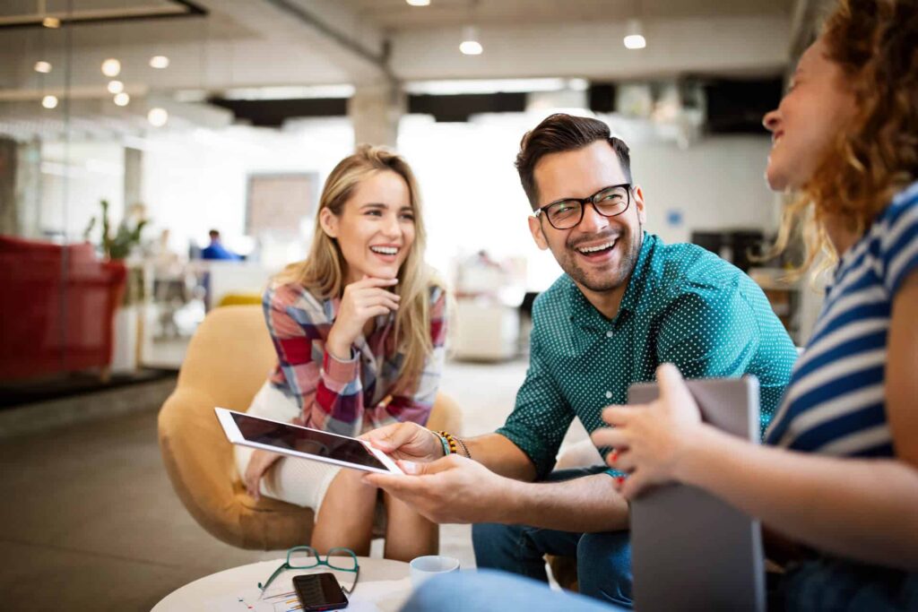 Three people sitting casually in an office, laughing together